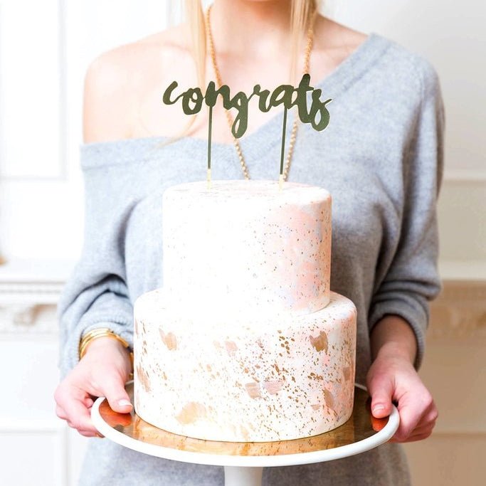 gold congrats cake topper on a white two tier cake