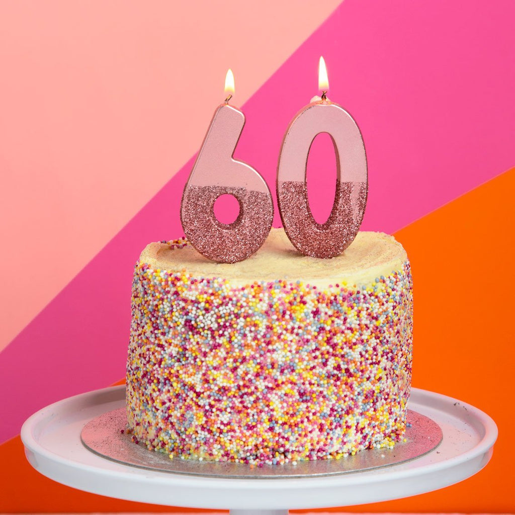 rose gold number candles with rose gold glitter on yellow cake with multicolored sprinkles