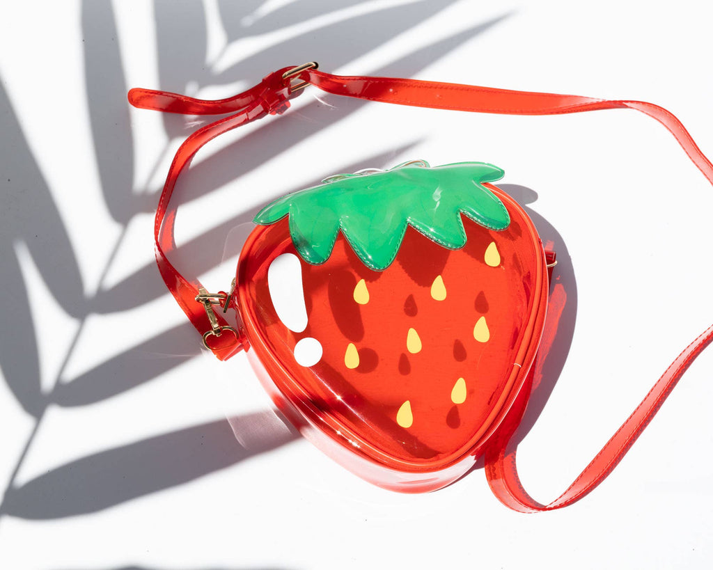 clear strawberry-shaped handbag with a red strap on a white background