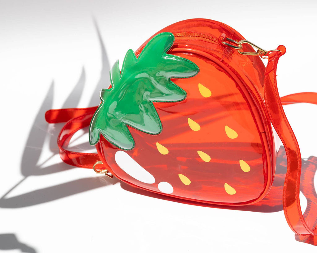 Strawberry-shaped clear red bag with green leaves on a white background